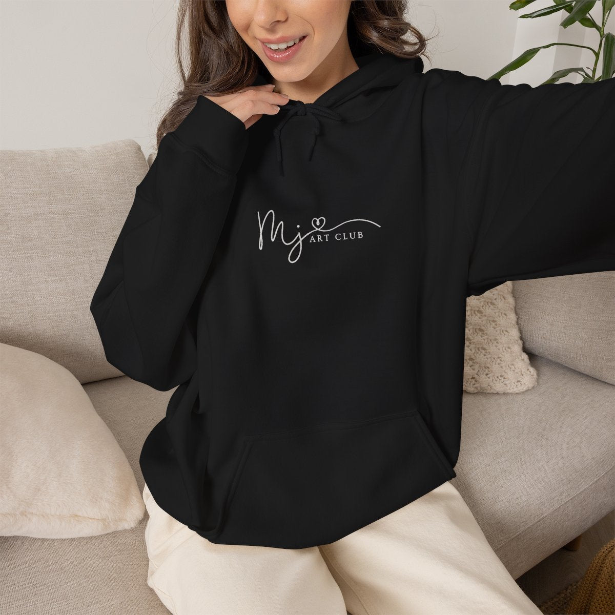 Person wearing a black hoodie with text, sitting on a couch.