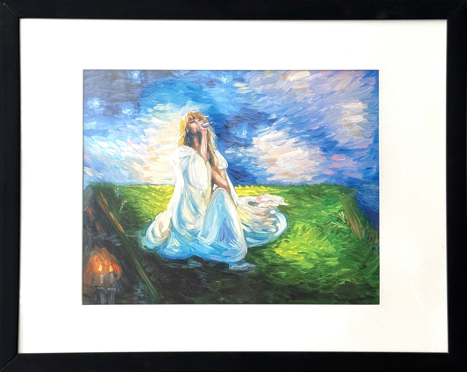 A framed art print featuring an impressionistic painting of a woman in a flowing white dress sitting on a green hill under a blue sky, mounted on a textured beige wall.