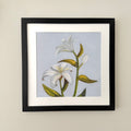 Black frame with white matting including a fine art print of two white lilies on a blue background.