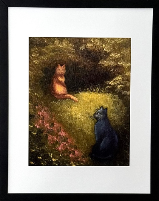 A framed art print featuring a painting of an orange cat and a black cat sitting in a grassy forest clearing, mounted on a light gray wall.