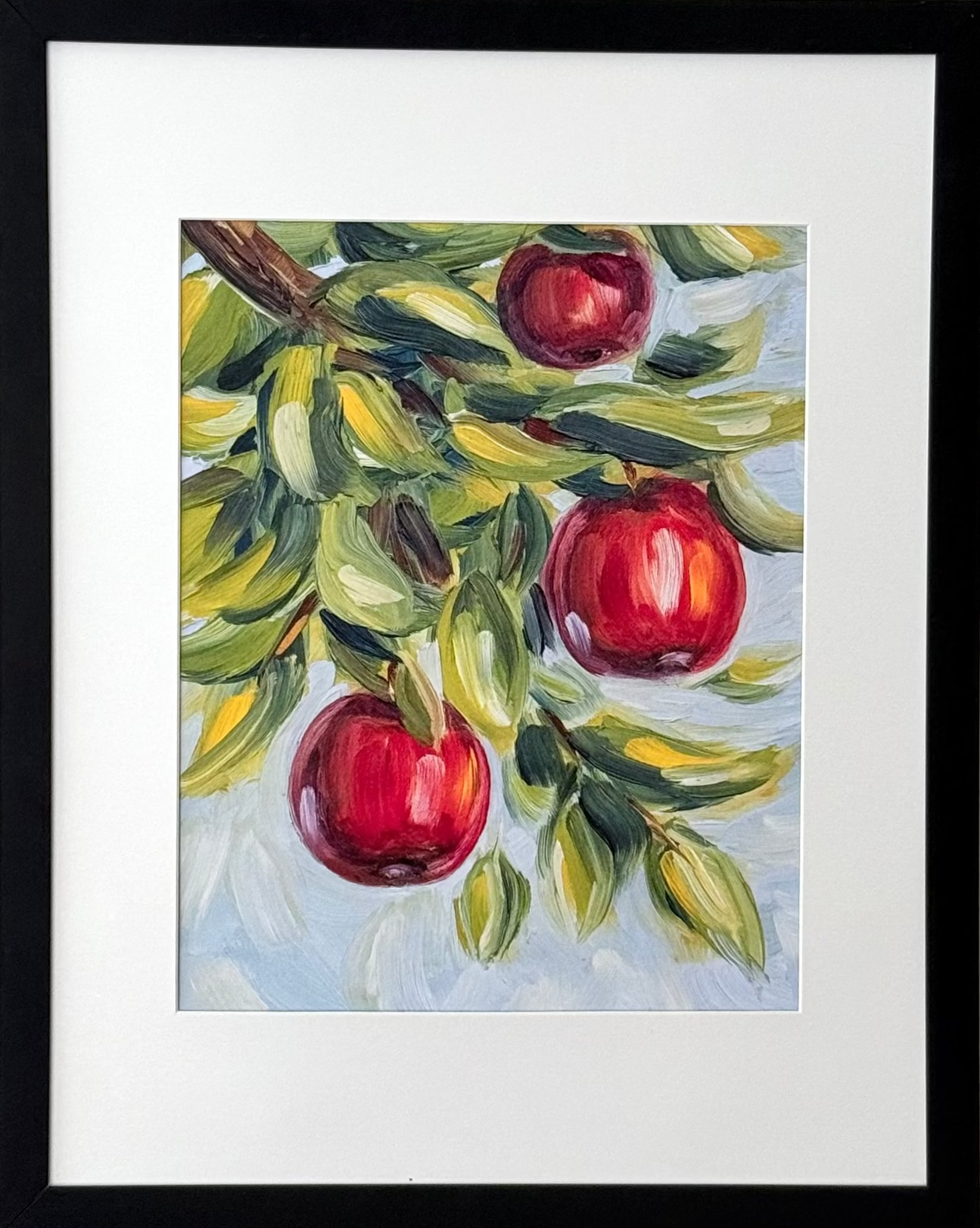 Framed wall art featuring a painted apple branch with three red apples, mounted on a light neutral wall.