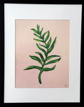 Framed botanical art print featuring a green leaf illustration on a soft pink background, matted with white and enclosed in a black frame, mounted on a light gray wall.
