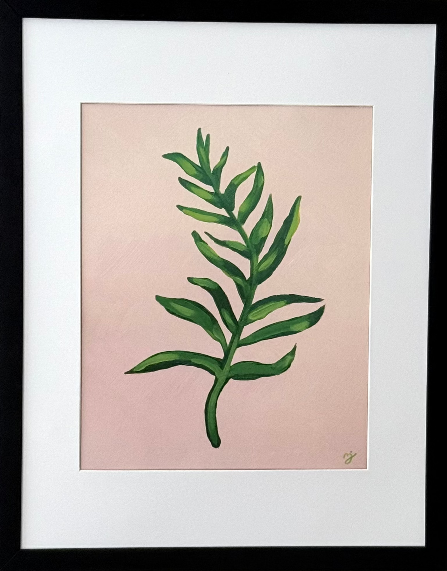 Framed botanical art print featuring a green leaf illustration on a soft pink background, matted with white and enclosed in a black frame, mounted on a light gray wall.