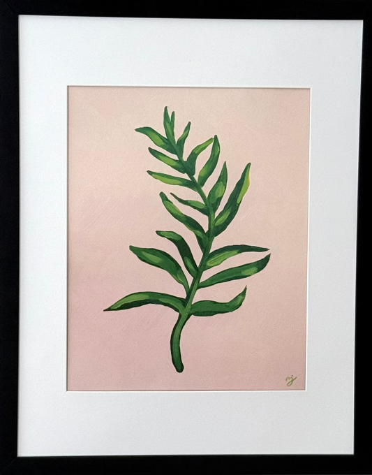 Framed botanical art print featuring a green leaf illustration on a soft pink background, matted with white and enclosed in a black frame, mounted on a light gray wall.