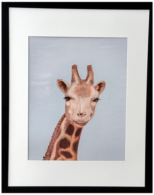 A framed art print featuring a painted giraffe head and neck against a pale blue-gray background, mounted on a light beige wall. The print has a white mat and is enclosed in a slim black frame.