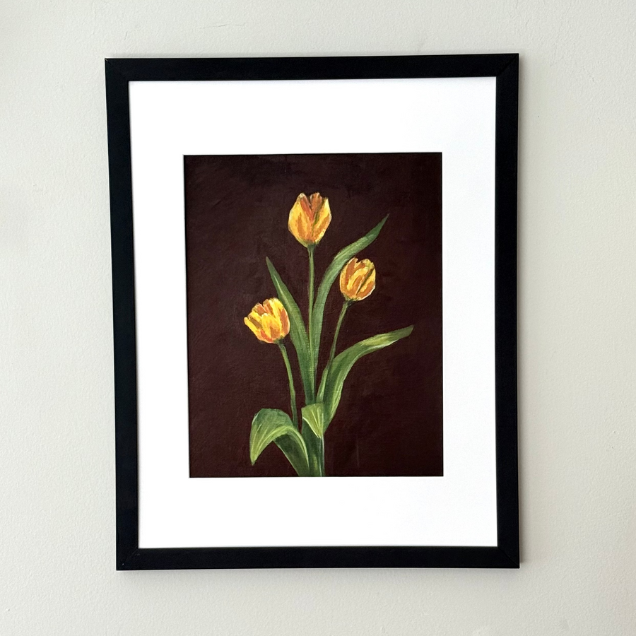 Framed art print of three yellow tulips on a brown background. 