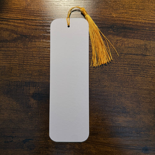 blank back side of a bookmark with a gold tassel against a wood background