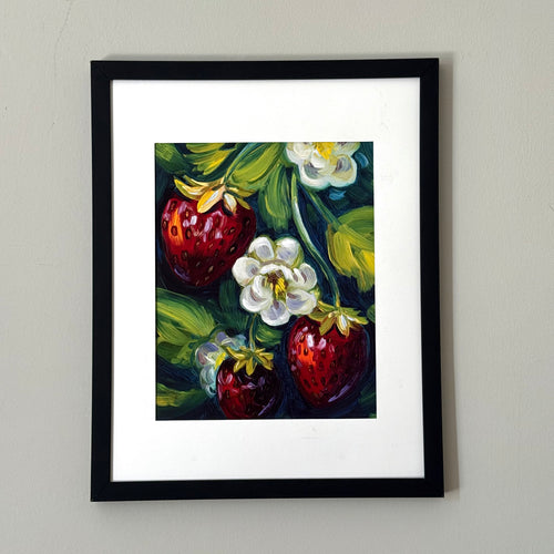 Print of a painting of three strawberries framed against a white wall