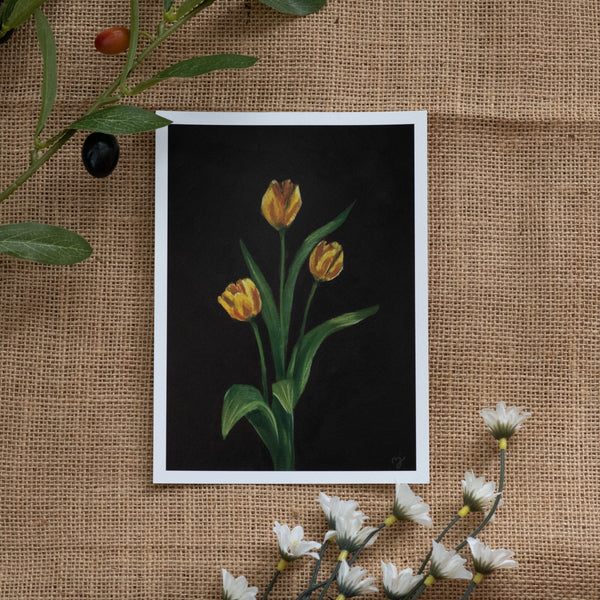 Burlap background with various floral decorations surrounding a fine art print depicting 3 yellow tulips on a brown background