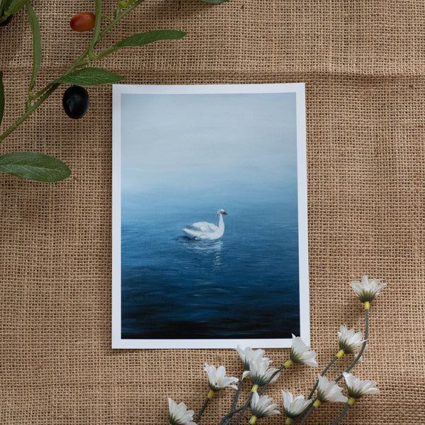 Burlap background with various floral decorations surrounding a fine art print depicting a white swan on a calm blue lake