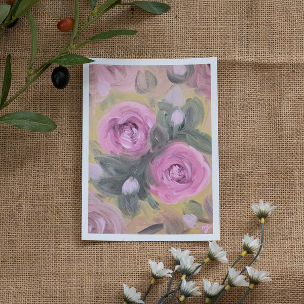 Burlap background with various floral decorations surrounding a fine art print depicting pink roses on a yellow background