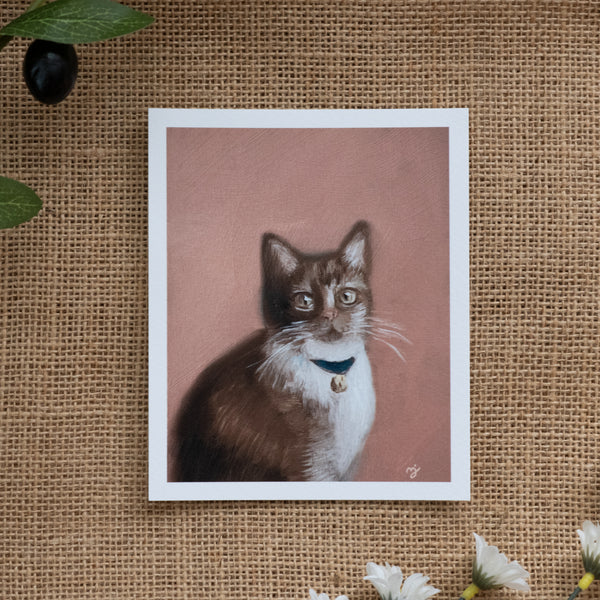 Burlap background with various floral decorations surrounding a fine art print depicting an orange cat on a muted orange background