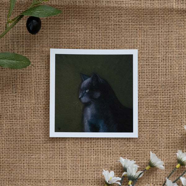 Burlap background with various floral decorations surrounding a fine art print depicting a dark grey cat against a green background