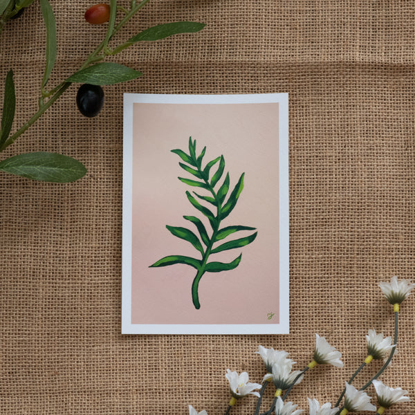 Burlap background with various floral decorations surrounding a fine art print depicting a green branch on a yellow orange gradient background